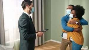 Two people hugging with masks on, and a salesman talking with them